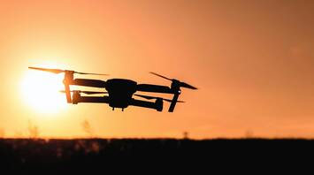Drone silhouetted against a sunset sky
