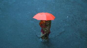 Woman with an umbrella wading through floodwaters