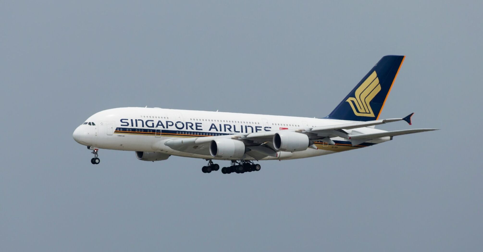 Singapore Airlines aircraft in flight against a gray sky