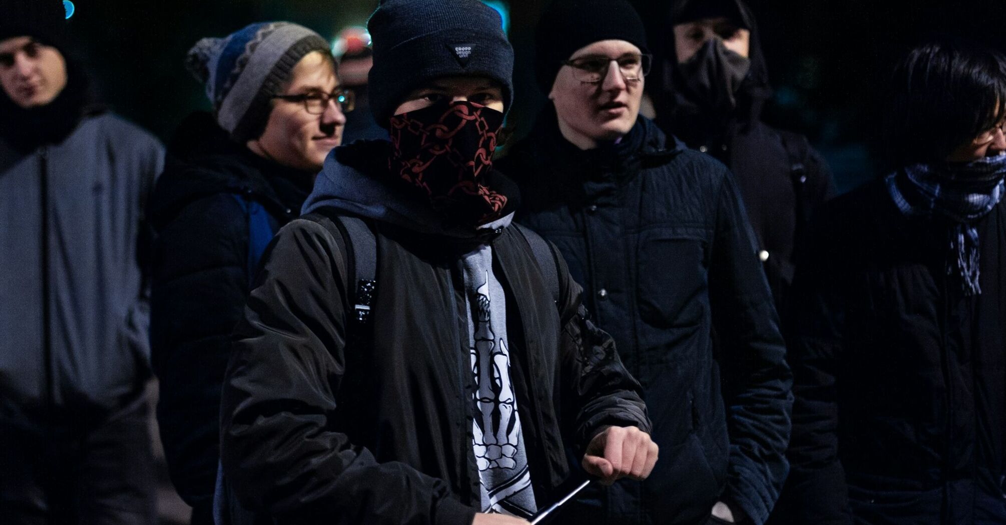 Group of masked young men gathered at night