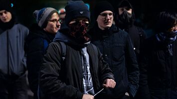 Group of masked young men gathered at night