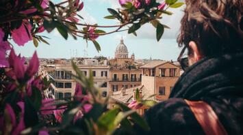 View of historic buildings and domed church in Italy, framed by pink flowers, with a person observing the scene