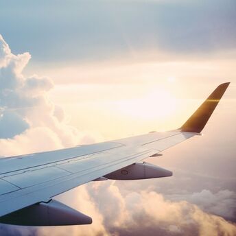 Airplane wing against a backdrop of clouds and sunrise