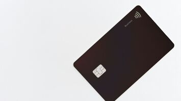 Black credit card with contactless symbol on white background