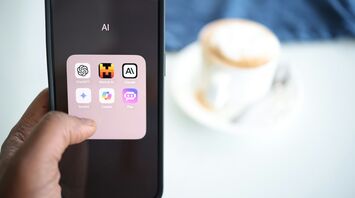 A smartphone screen displaying various AI applications, with a blurred background showing a cup of coffee