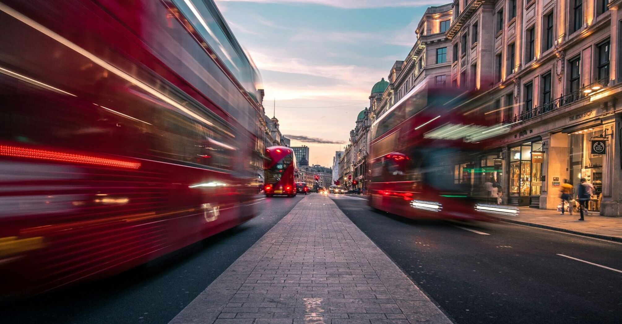 Blurred red buses on a London street at sunset