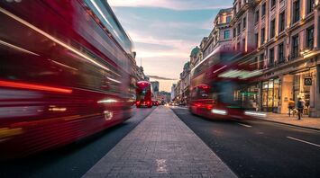 Blurred red buses on a London street at sunset