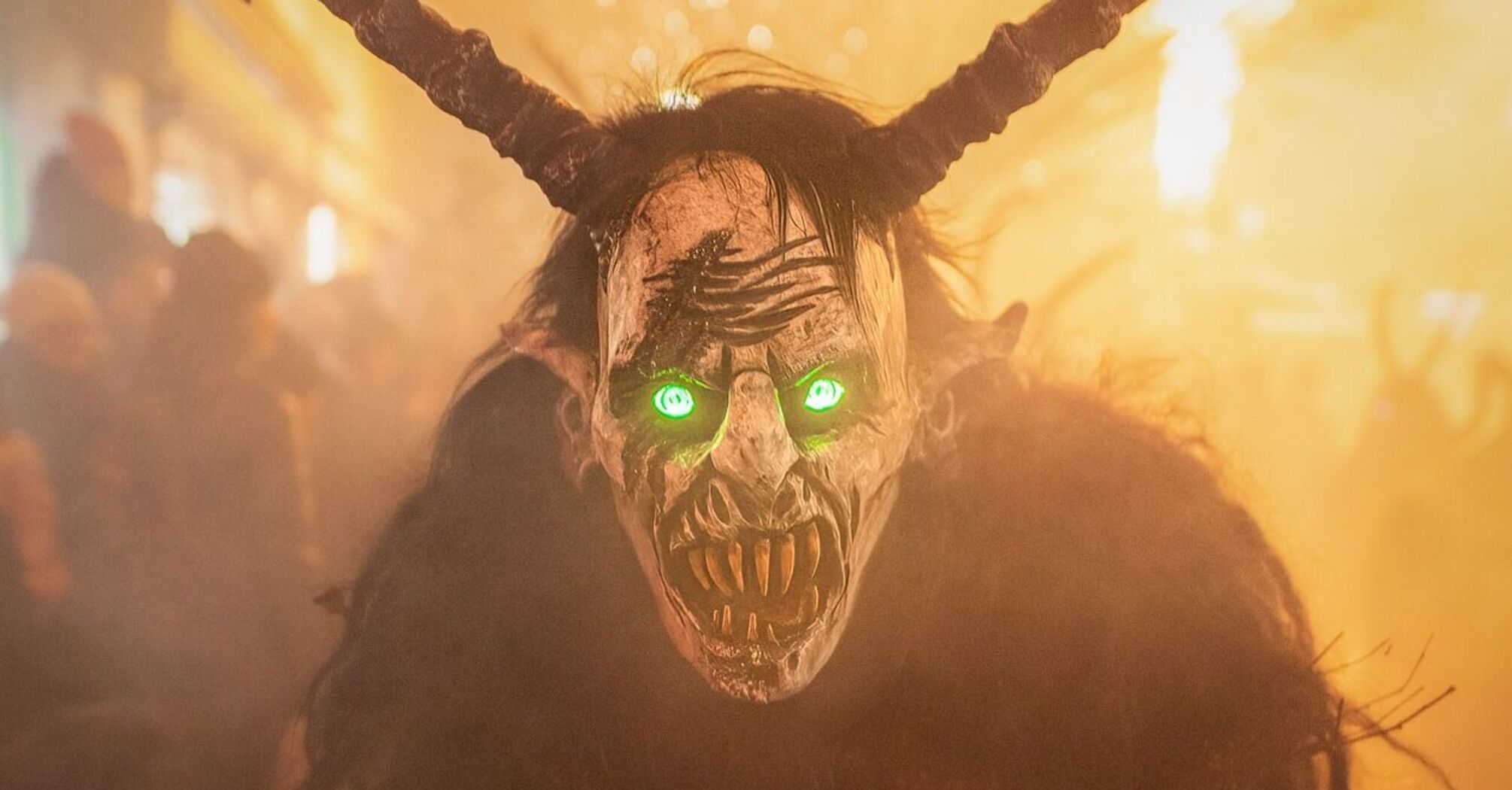 A person dressed as Krampus with glowing green eyes during a festival in Austria