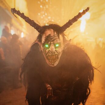 A person dressed as Krampus with glowing green eyes during a festival in Austria