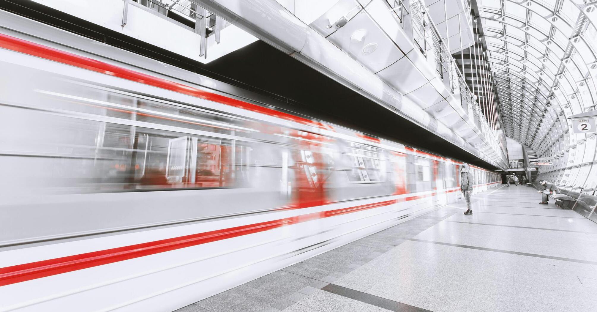 Modern metro station with a red-and-white train in motion