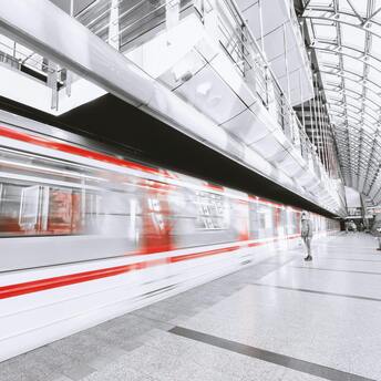Modern metro station with a red-and-white train in motion