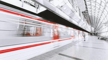 Modern metro station with a red-and-white train in motion