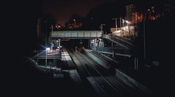 A dimly lit train station at night undergoing repairs with empty tracks and maintenance equipment