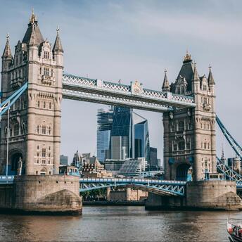 Tower Bridge in London with modern skyscrapers in the background and a boat on the River Thames in the foreground