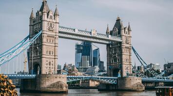 Tower Bridge in London with modern skyscrapers in the background and a boat on the River Thames in the foreground
