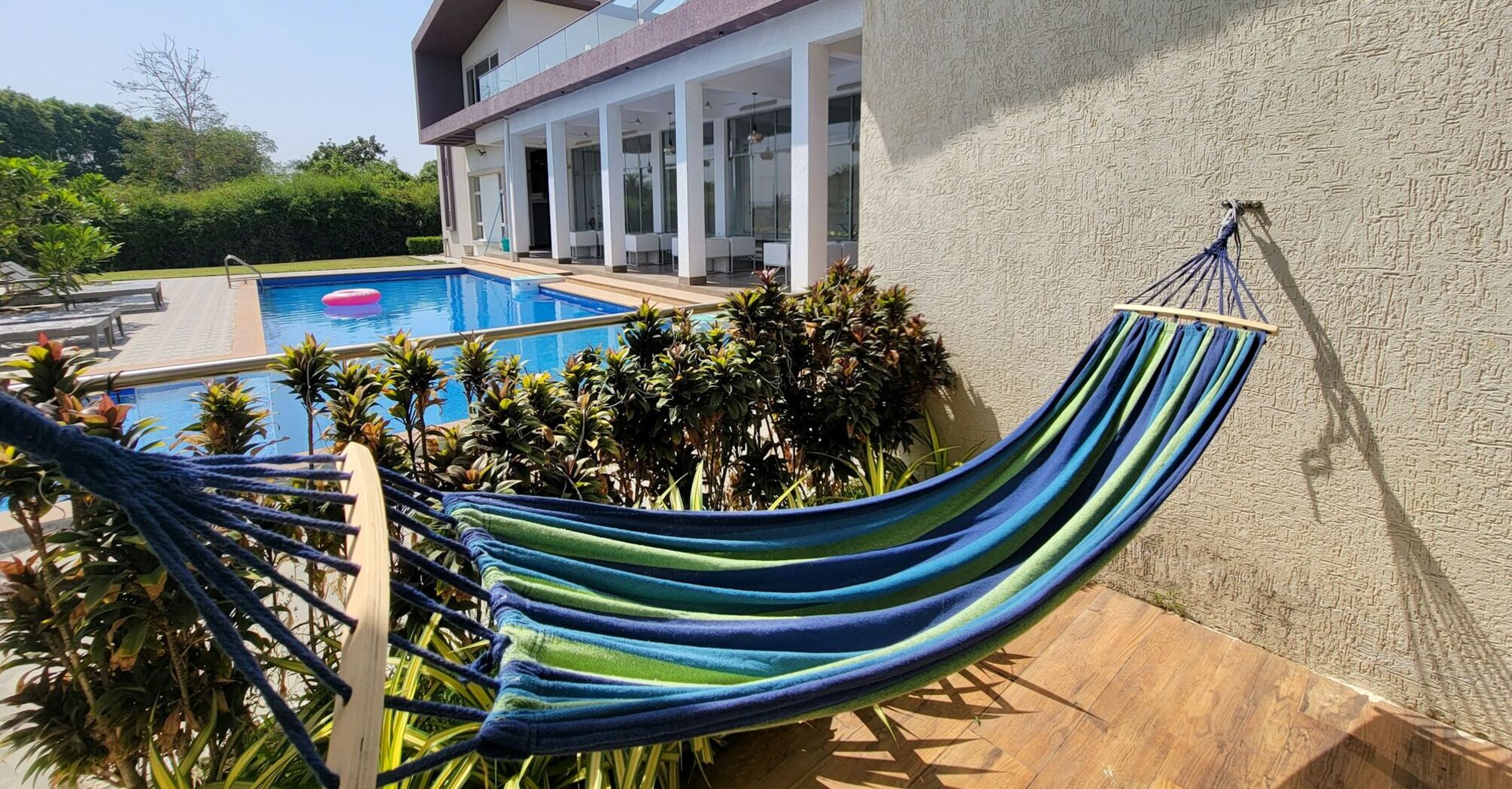 A modern villa with a pool and hammock under clear skies