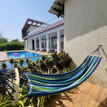 A modern villa with a pool and hammock under clear skies