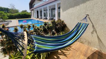 A modern villa with a pool and hammock under clear skies