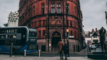 A historic red brick building in Nottingham with a blue double-decker bus in the foreground