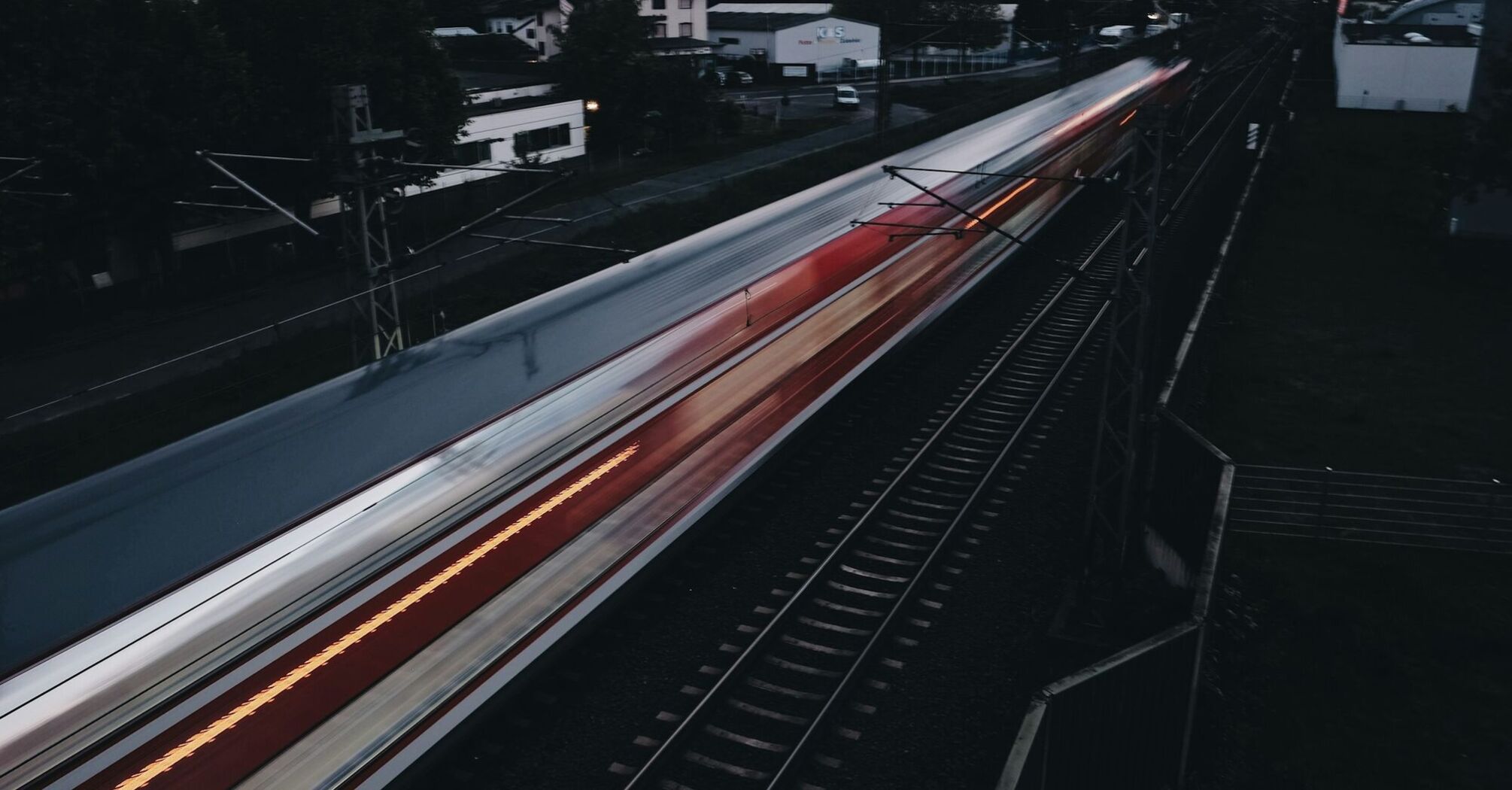 A high-speed train in motion on railway tracks during twilight