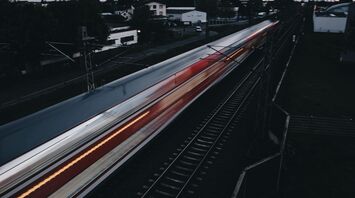 A high-speed train in motion on railway tracks during twilight