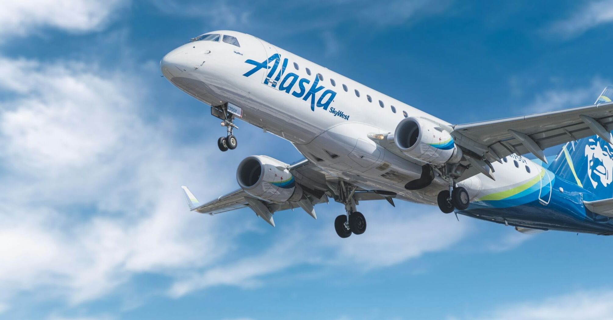 Alaska Airlines plane taking off against a blue sky