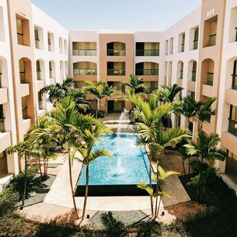 A courtyard with a fountain surrounded by palm trees at a modern hotel