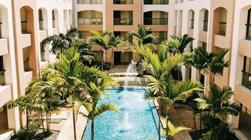 A courtyard with a fountain surrounded by palm trees at a modern hotel