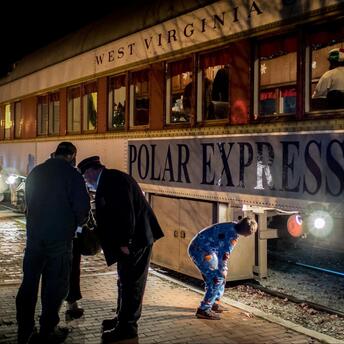 Passengers boarding the Polar Express train in festive attire at a station