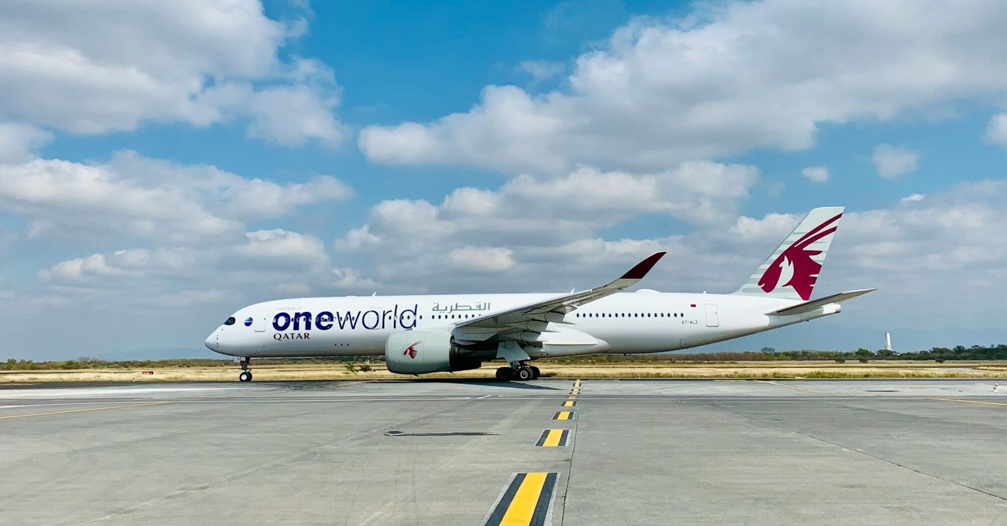 Qatar Airways aircraft on a runway under a clear blue sky