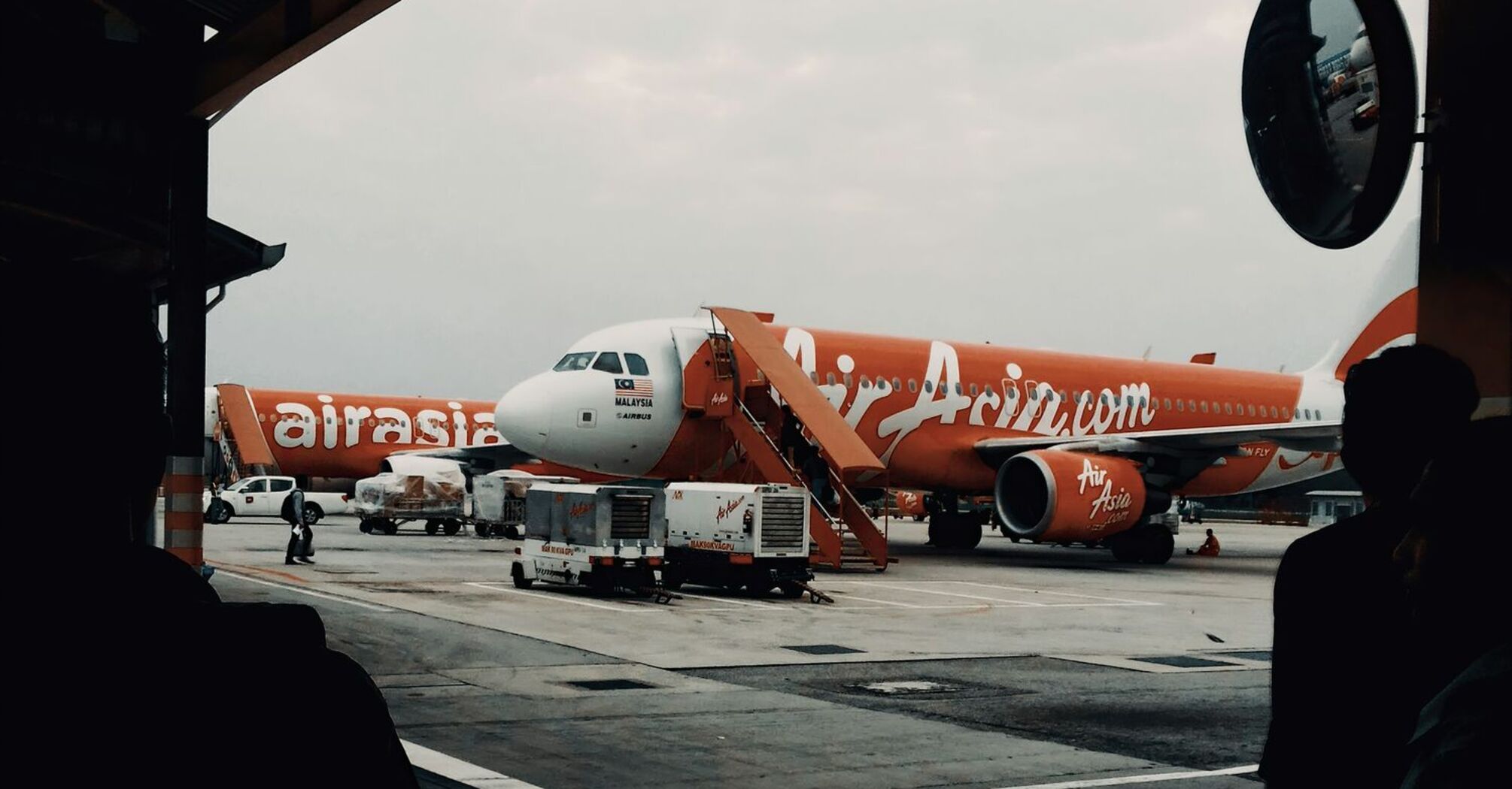 An AirAsia airplane parked at the airport tarmac with a mobile staircase in front for boarding