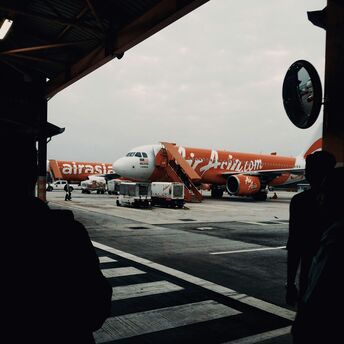 An AirAsia airplane parked at the airport tarmac with a mobile staircase in front for boarding