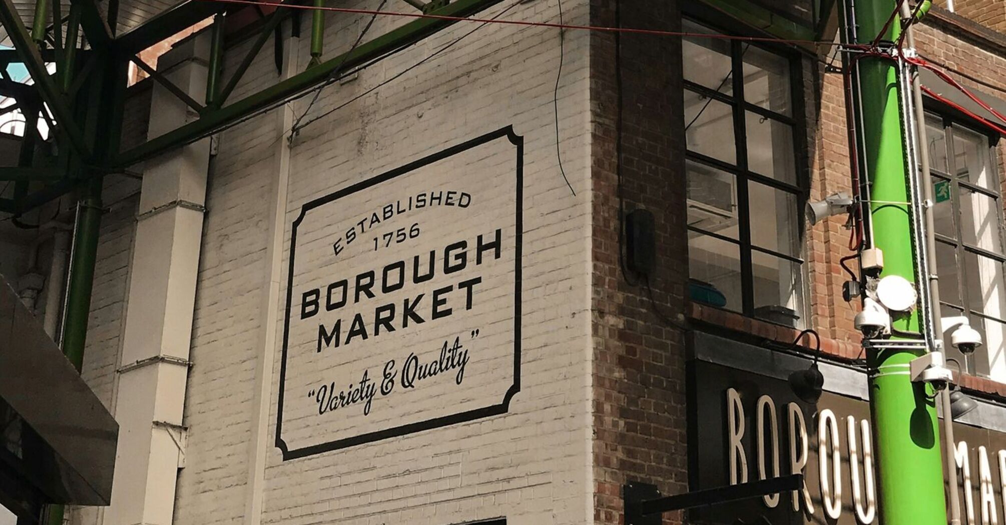 Exterior view of Borough Market in London with its iconic green steel structure and signage