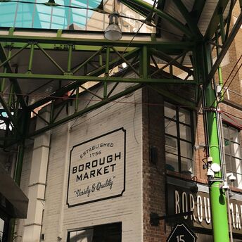Exterior view of Borough Market in London with its iconic green steel structure and signage