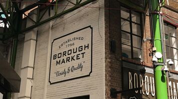 Exterior view of Borough Market in London with its iconic green steel structure and signage