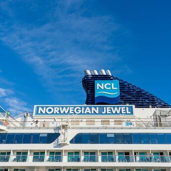 A cruise ship under clear blue skies with the NCL logo prominently displayed