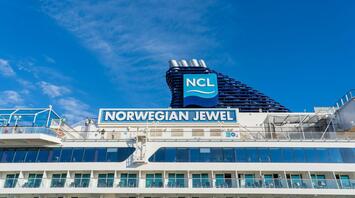 A cruise ship under clear blue skies with the NCL logo prominently displayed