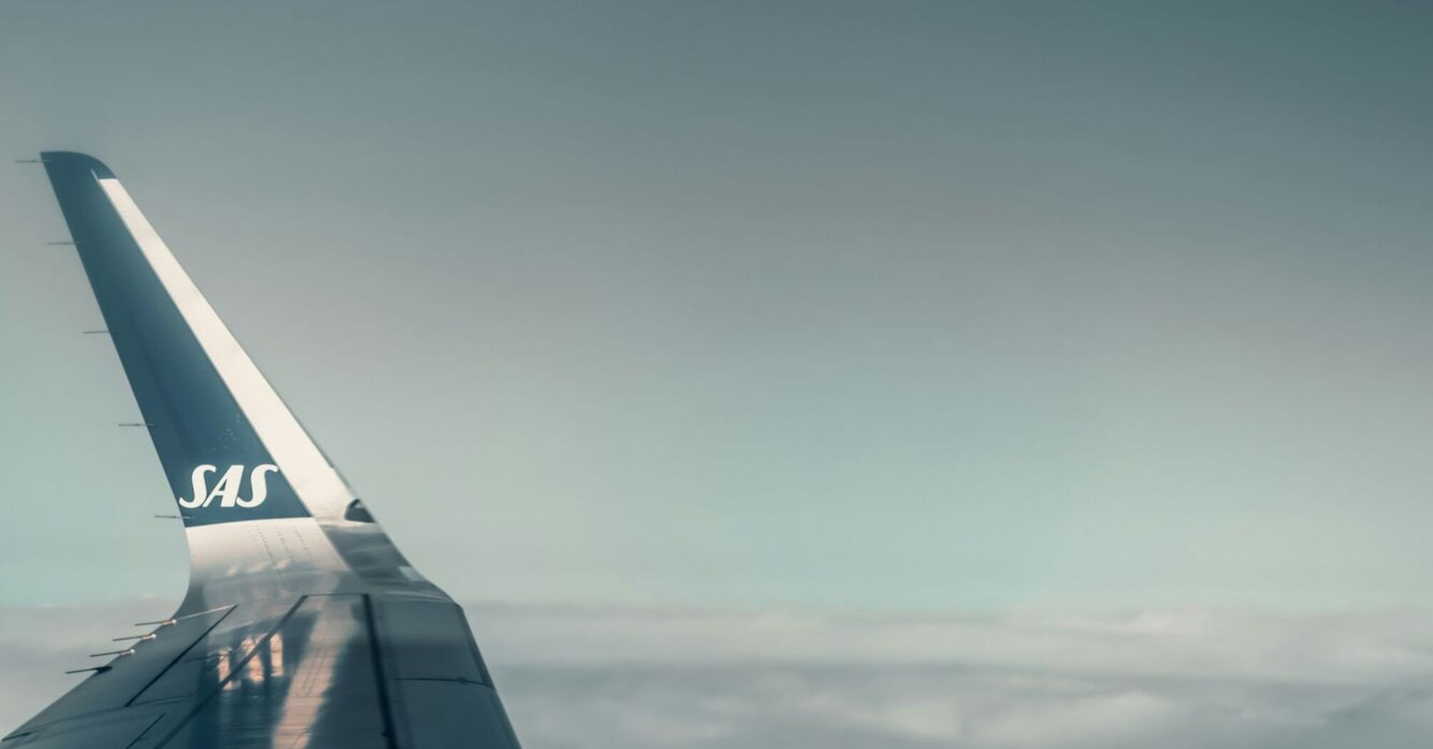 SAS airplane wing in flight above clouds