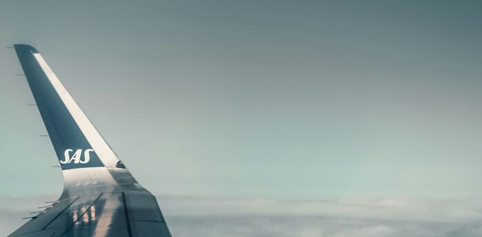 SAS airplane wing in flight above clouds