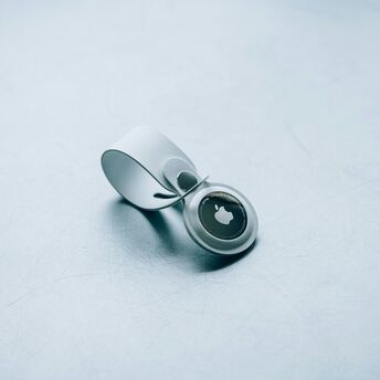 Apple AirTag with white keyring on a textured surface