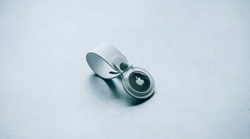 Apple AirTag with white keyring on a textured surface
