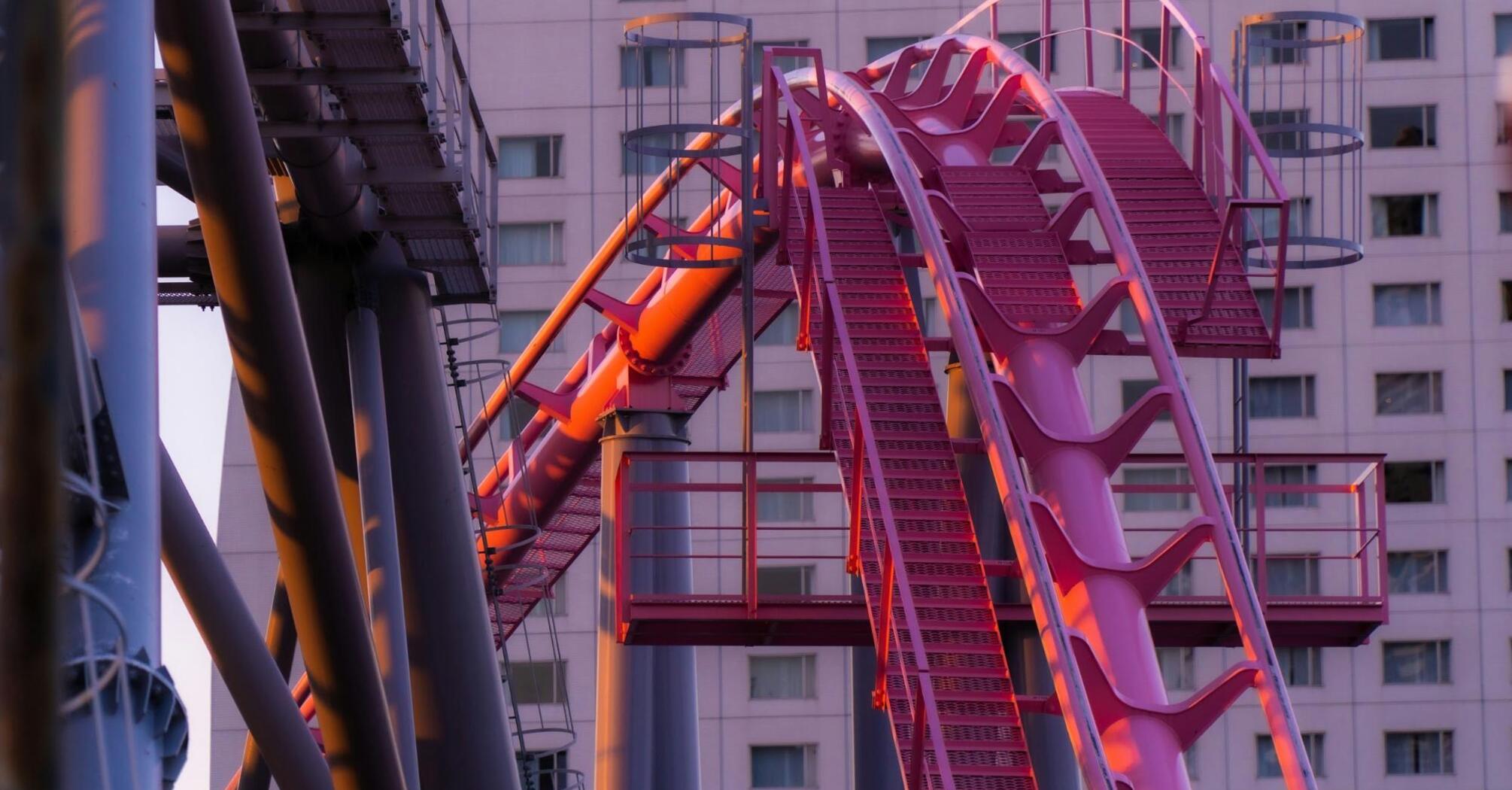 Close-up of a pink roller coaster track in an urban amusement park