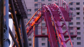 Close-up of a pink roller coaster track in an urban amusement park