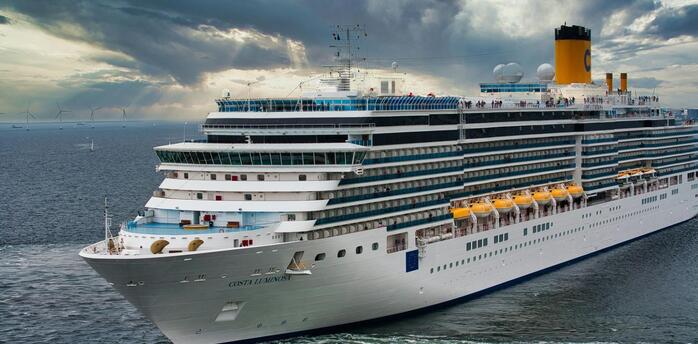 A large modern cruise ship sailing in open waters under a dramatic cloudy sky