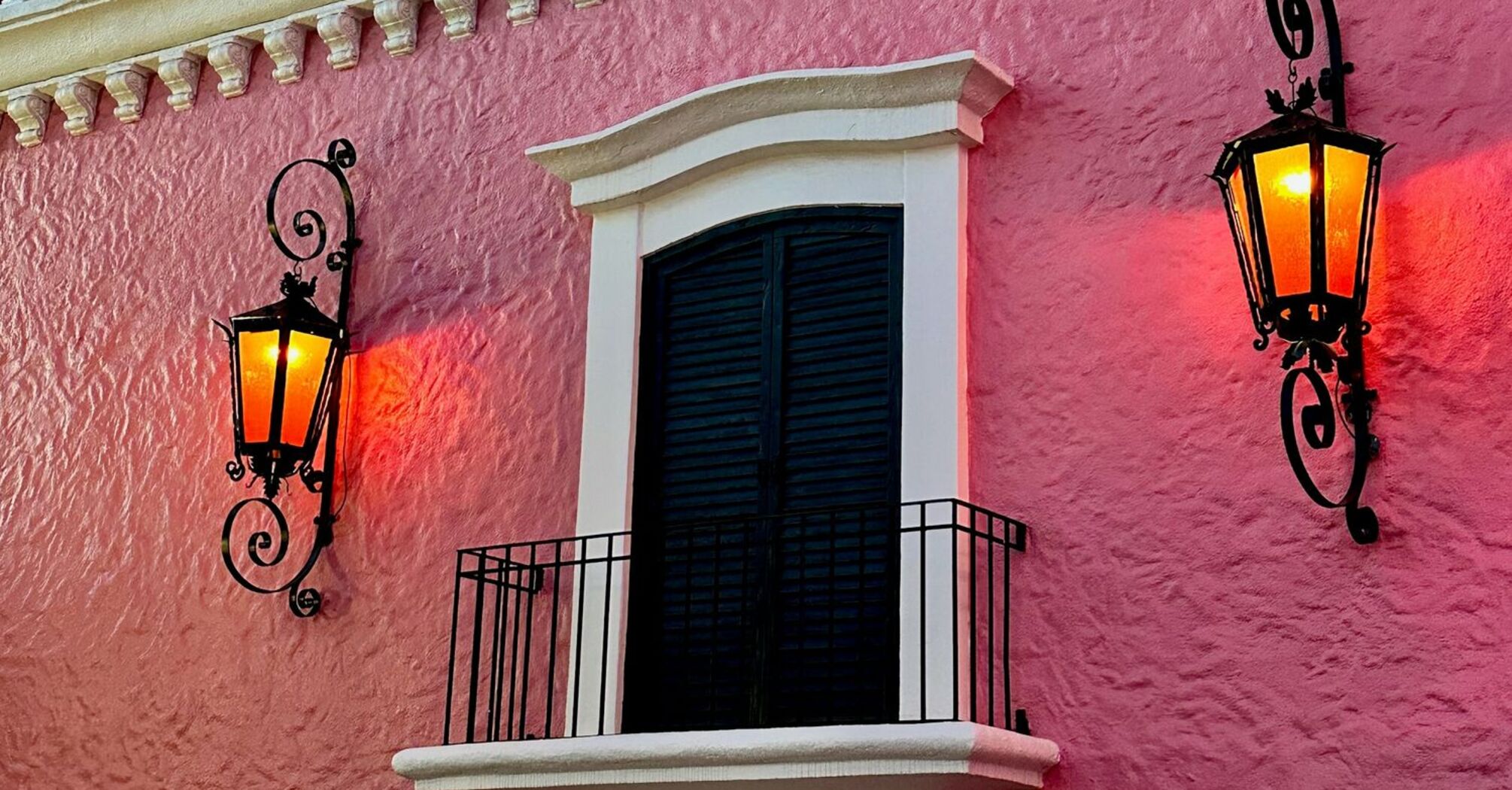 Pink facade of Casa Bonita with ornate balcony and lanterns