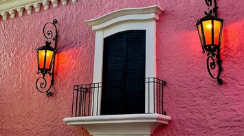 Pink facade of Casa Bonita with ornate balcony and lanterns