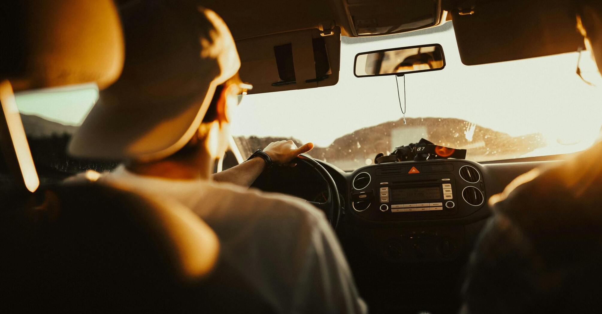 A person driving a car at sunset