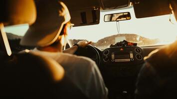 A person driving a car at sunset