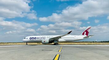A Qatar Airways airplane featuring the oneworld alliance logo on a runway under a clear sky