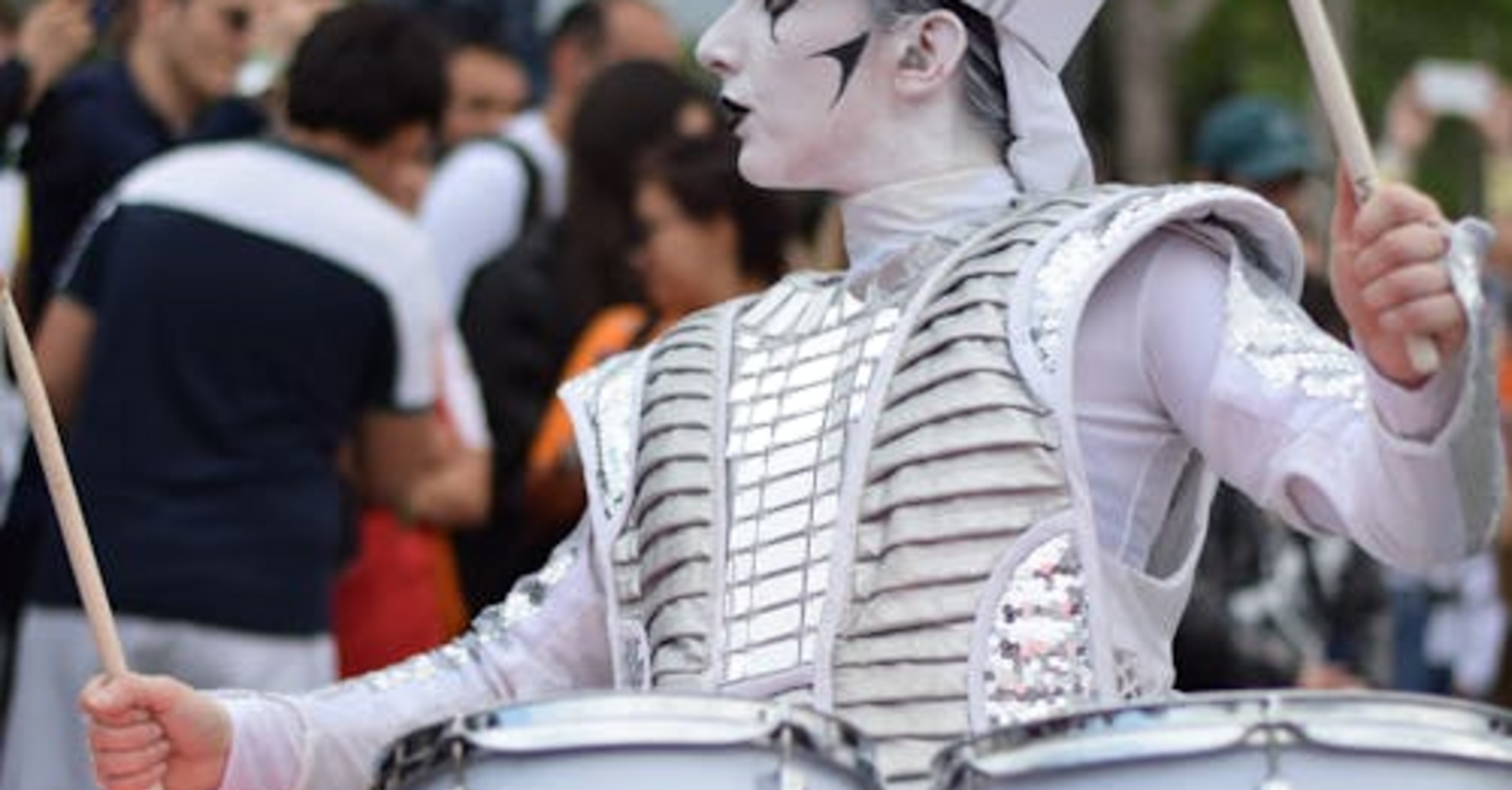 A performer in futuristic attire playing LED drums at a LED Drumming Parade